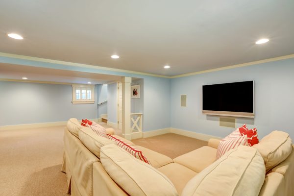 61882638 - spacious basement living room interior in pastel blue tones. beige carpet floor and large corner sofa with tv. northwest, usa